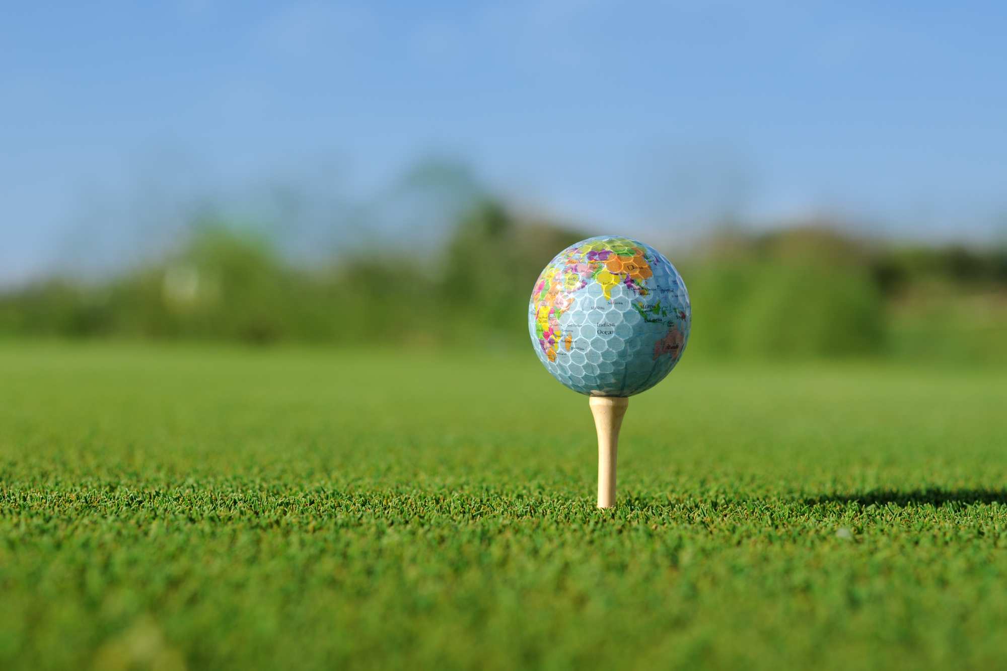 A golf ball with earth motive sitting on a peg